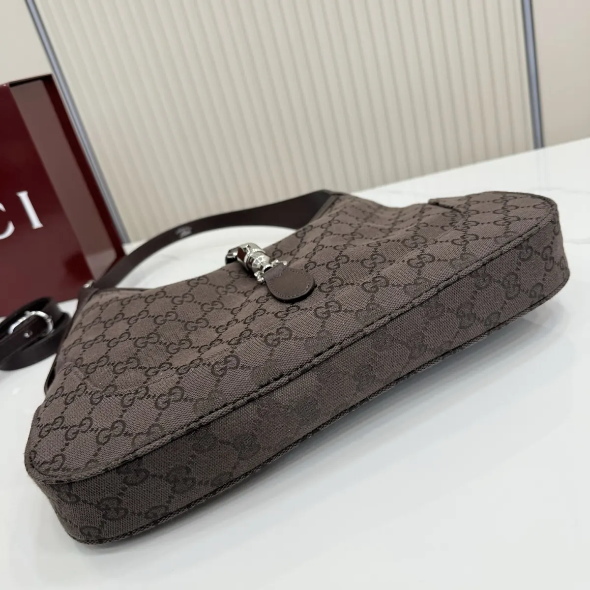 p530。【配全套包装】‼️2026春夏系列全新上市。这款Gucci Jackie 1961系列手袋在《La Famiglia》系列的&rdquo;La It Girl&ldquo;造型种呈现。包身选用轻盈但结构挺括的GG帆布，演绎复古灵感的沙色，搭配便于使用的金色调推入式锁扣设计，更添品牌魅力。 深棕色GG帆布 深棕色软皮皮革滚边 银色调配件 深棕色帆布衬里，饰钻石菱格纹图案 内部：1个拉链口袋 可调节提手长度：25 - 29cm 可调节延长肩带高：48 - 61cm 饰推入式锁扣 型号：863136。 尺寸：31.5厘米（宽）x 22厘米（高）x 4.5厘米（深） 重量：约0.35千克 颜色：深棕色/帆布。 意大利创作