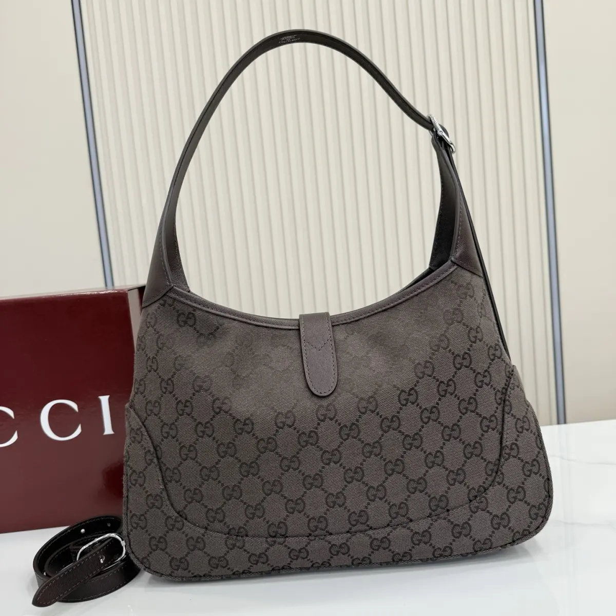 p530。【配全套包装】‼️2026春夏系列全新上市。这款Gucci Jackie 1961系列手袋在《La Famiglia》系列的&rdquo;La It Girl&ldquo;造型种呈现。包身选用轻盈但结构挺括的GG帆布，演绎复古灵感的沙色，搭配便于使用的金色调推入式锁扣设计，更添品牌魅力。 深棕色GG帆布 深棕色软皮皮革滚边 银色调配件 深棕色帆布衬里，饰钻石菱格纹图案 内部：1个拉链口袋 可调节提手长度：25 - 29cm 可调节延长肩带高：48 - 61cm 饰推入式锁扣 型号：863136。 尺寸：31.5厘米（宽）x 22厘米（高）x 4.5厘米（深） 重量：约0.35千克 颜色：深棕色/帆布。 意大利创作