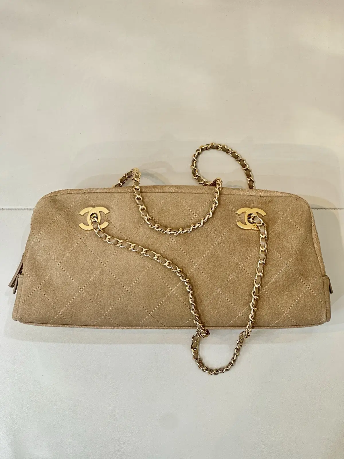 6406 Chanel 26A 新款麂皮腋下法棍包 \n秋冬一到麂皮款直接杀回来！这只香家卡其麂皮长法棍，真的属于越看越有味道的宝藏款，第一眼就被这个复古氛围感拿捏住。\n区别于常规单双C包款，包身左右对称双C金标设计，辨识度直接拉满。包身精选卡其麂皮面料，上手软糯细腻，菱格车线工整利落，纹路均匀饱满，不是廉麂皮能比的。\n包身两侧做拉链开合，拿取物品很方便，内里空间充足，手机、粉饼、钥匙通通装下。\n老渠道牛货！正单出来的麂皮质感真的不一样，皮料的绒感、菱格走线、五金的色泽，市面普通版本很难。不撞款的小众长法棍，偏爱复古麂皮的姐妹，这只闭眼入！\n尺寸15-32-8cm