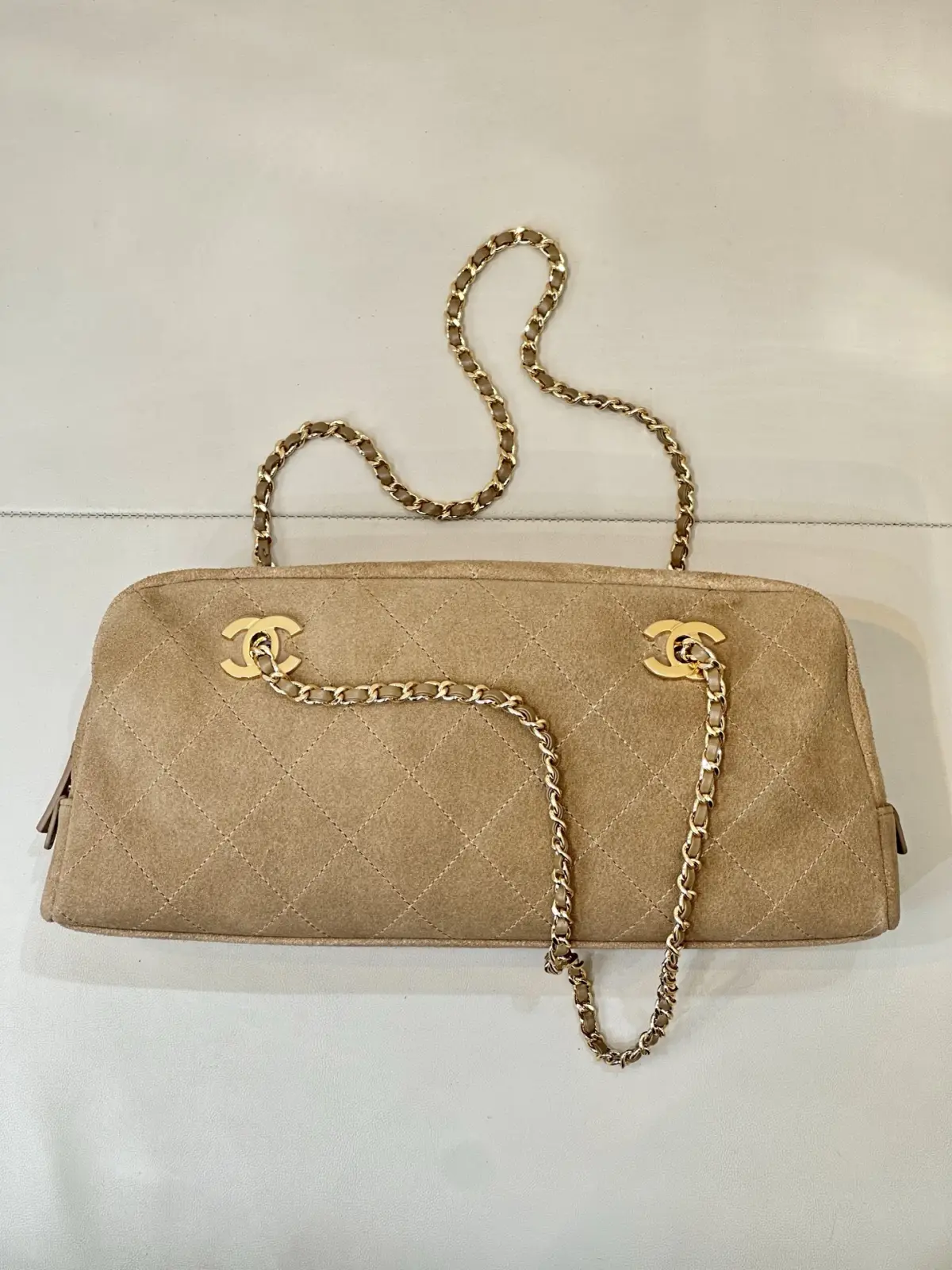 6406 Chanel 26A 新款麂皮腋下法棍包 \n秋冬一到麂皮款直接杀回来！这只香家卡其麂皮长法棍，真的属于越看越有味道的宝藏款，第一眼就被这个复古氛围感拿捏住。\n区别于常规单双C包款，包身左右对称双C金标设计，辨识度直接拉满。包身精选卡其麂皮面料，上手软糯细腻，菱格车线工整利落，纹路均匀饱满，不是廉麂皮能比的。\n包身两侧做拉链开合，拿取物品很方便，内里空间充足，手机、粉饼、钥匙通通装下。\n老渠道牛货！正单出来的麂皮质感真的不一样，皮料的绒感、菱格走线、五金的色泽，市面普通版本很难。不撞款的小众长法棍，偏爱复古麂皮的姐妹，这只闭眼入！\n尺寸15-32-8cm