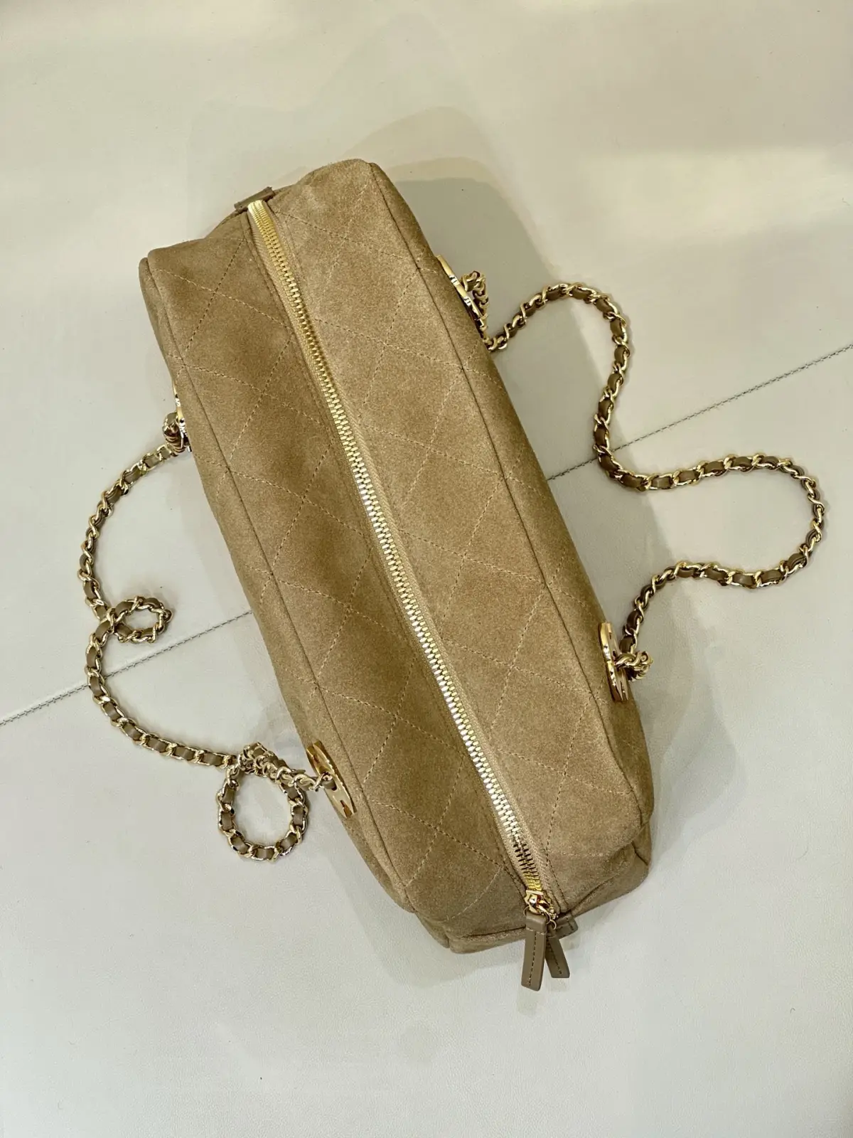 6406 Chanel 26A 新款麂皮腋下法棍包 \n秋冬一到麂皮款直接杀回来！这只香家卡其麂皮长法棍，真的属于越看越有味道的宝藏款，第一眼就被这个复古氛围感拿捏住。\n区别于常规单双C包款，包身左右对称双C金标设计，辨识度直接拉满。包身精选卡其麂皮面料，上手软糯细腻，菱格车线工整利落，纹路均匀饱满，不是廉麂皮能比的。\n包身两侧做拉链开合，拿取物品很方便，内里空间充足，手机、粉饼、钥匙通通装下。\n老渠道牛货！正单出来的麂皮质感真的不一样，皮料的绒感、菱格走线、五金的色泽，市面普通版本很难。不撞款的小众长法棍，偏爱复古麂皮的姐妹，这只闭眼入！\n尺寸15-32-8cm